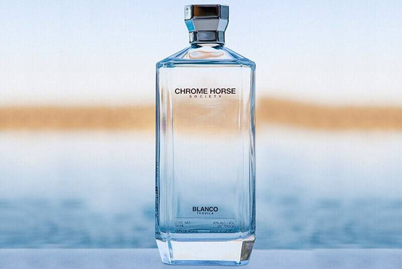 Chrome Horse Society blanco tequila bottle against a blurred sea view